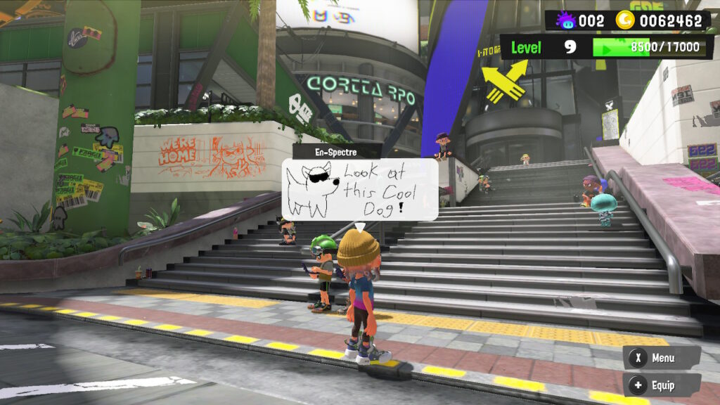 In-game screenshot of hub world in Splatoon 3, with a player with a drawing displayed above them.