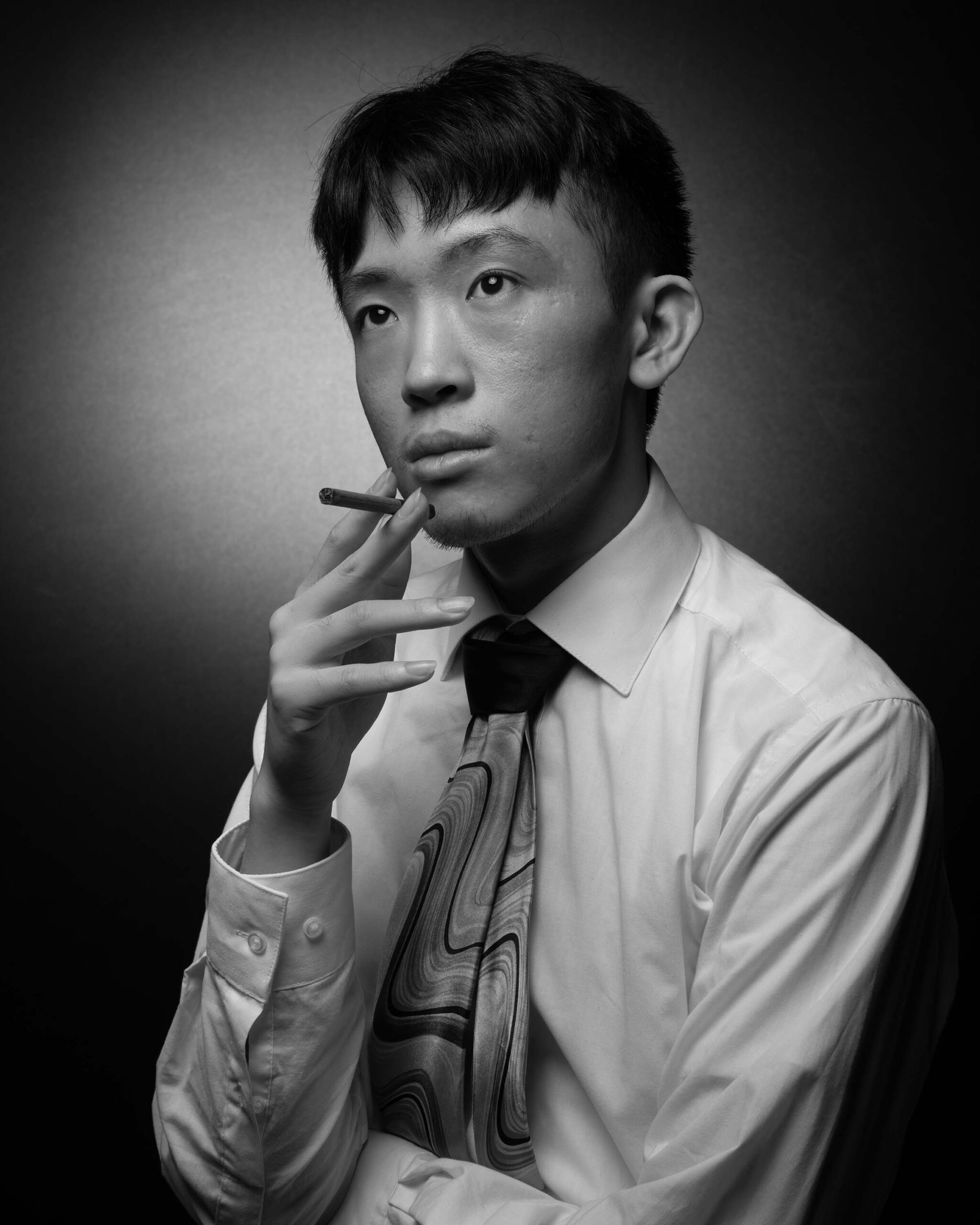 Man looks off to the left, holding a cigarette.