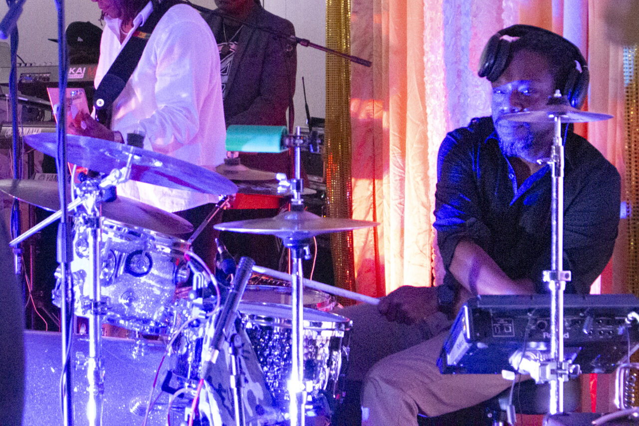 The drummer of The Hardcore Band looking at the camera behind his drumkit